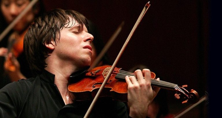 a young man playing the violin in front of other musicians