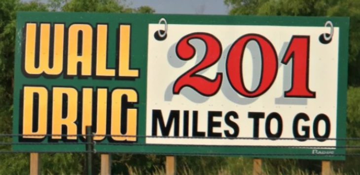 a large sign advertising wall drug miles to go