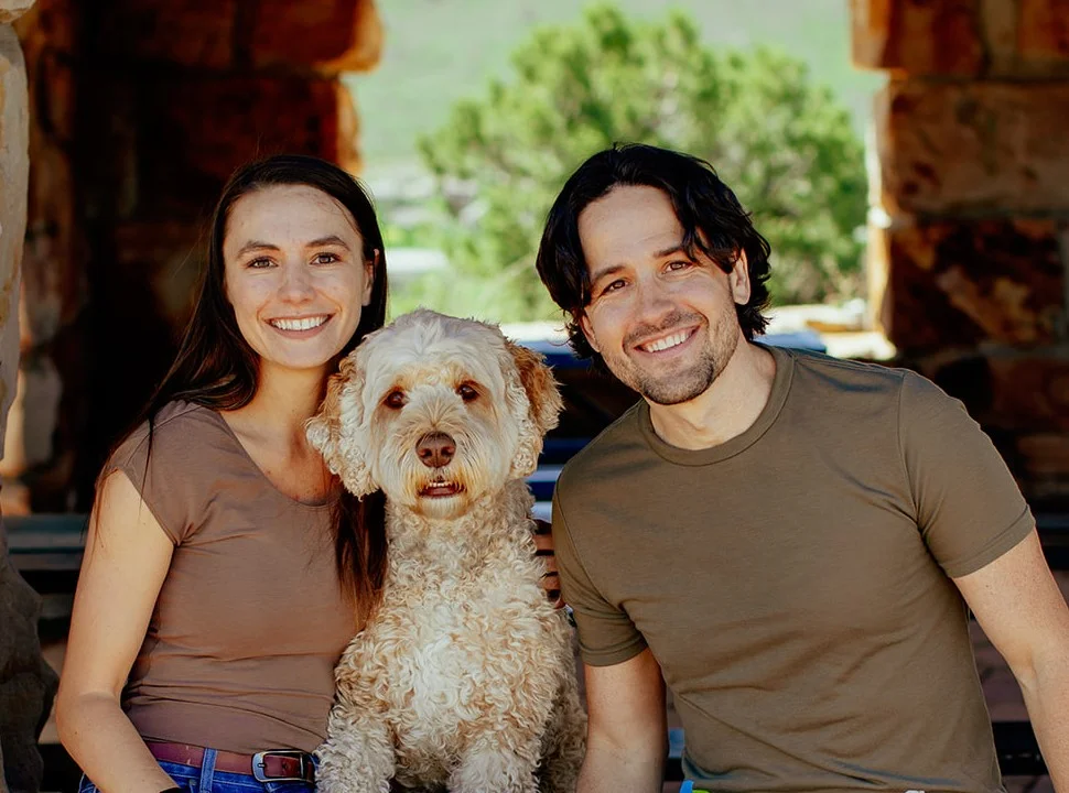 a man and woman sitting on a bench with a dog