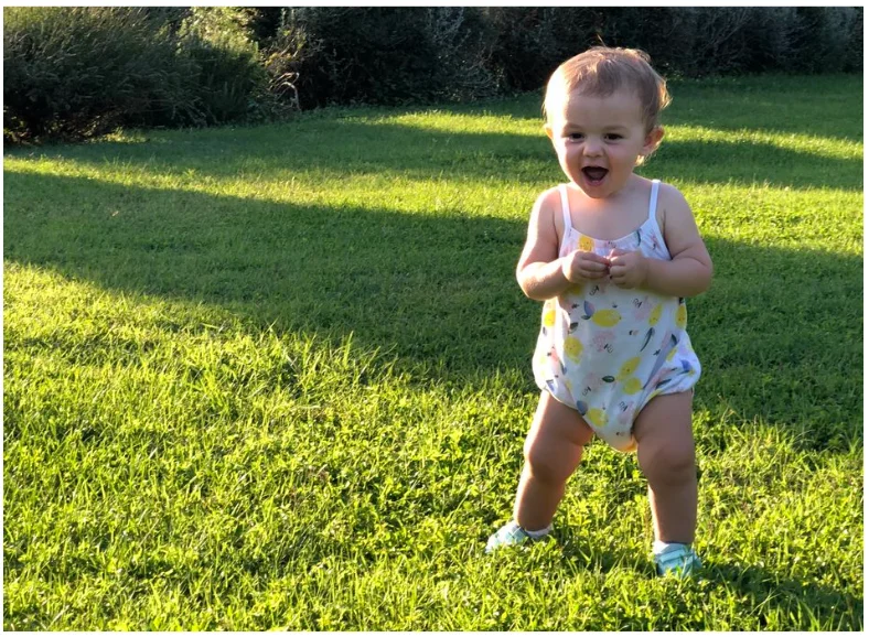 a little girl standing on top of a lush green field