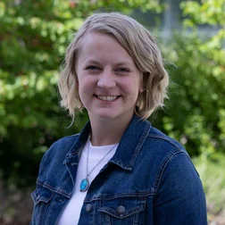 a woman in a jean jacket smiling for the camera