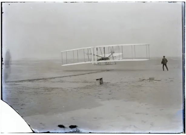 an old photo of a man standing next to a plane