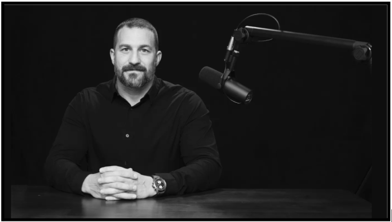 a man sitting at a table in front of a microphone