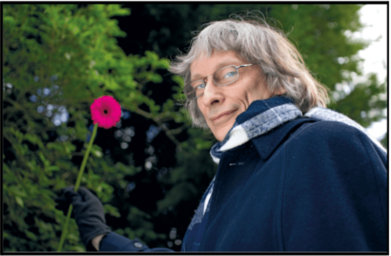 an older woman holding a pink flower in her hand